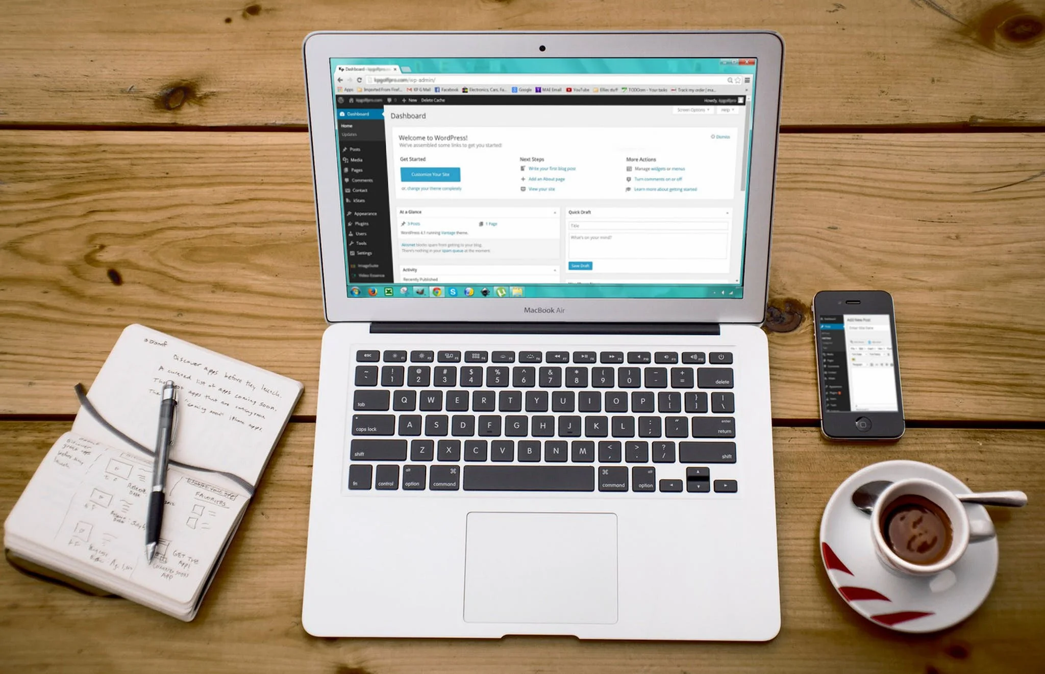 macbook with wordpress on the screen sitting on desktop with notebook phone and cup of coffee